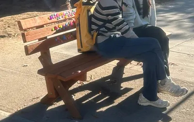 A bench bedazzled with colorful plastic rhinestones, with two people sitting on it.